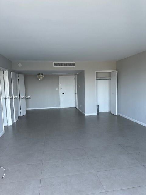 An empty room features gray tile flooring, white walls, and several closed white doors — 5161 Collins Ave # 1709, Miami Beach FL 33140, MIAMI BEACH, FL