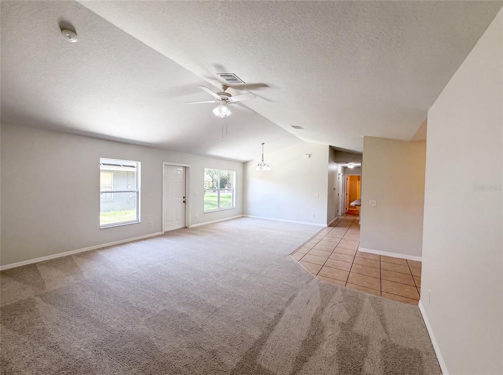 A living room with vaulted ceilings, beige carpeting, and a tiled entryway — 306 GARDEN OAK COURT, APOPKA, FL