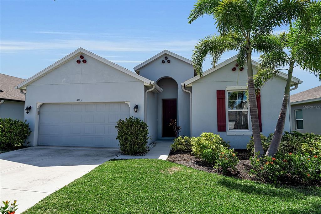 A single-story house with a two-car garage, light blue stucco exterior, and a palm tree — 4505 WINDY HAMMOCK WAY, PALMETTO, FL