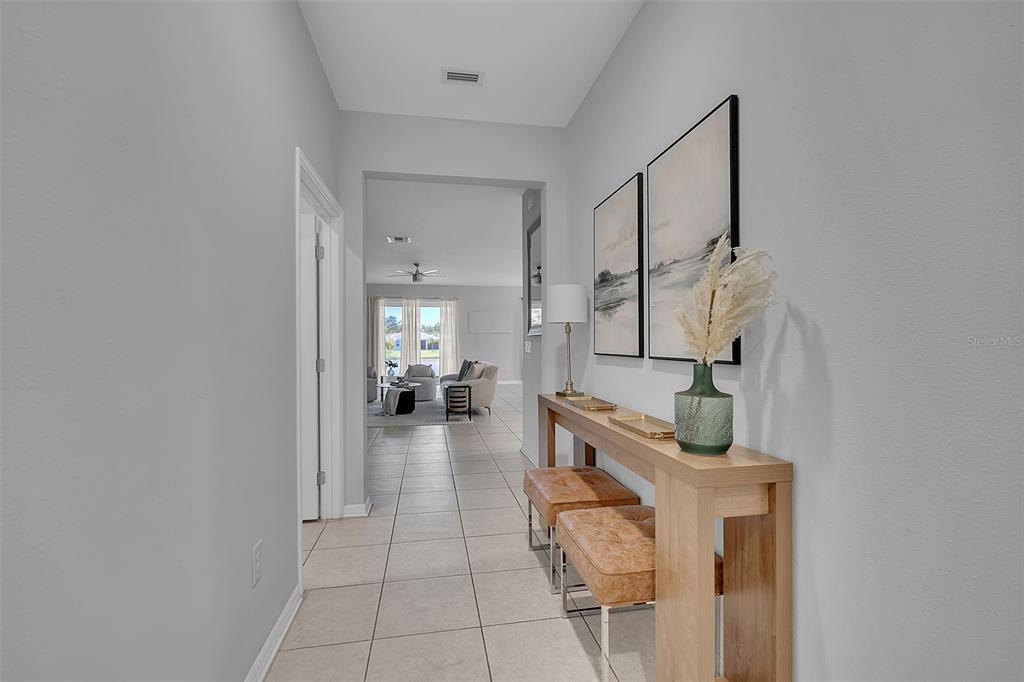 A hallway with light tile flooring leads to a living area featuring a console table — 4505 WINDY HAMMOCK WAY, PALMETTO, FL