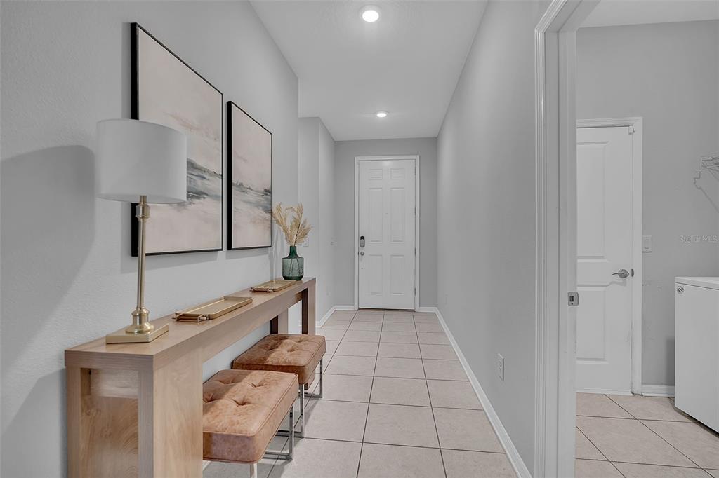 A hallway features a console table with two stools, wall art, and light-colored tile flooring — 4505 WINDY HAMMOCK WAY, PALMETTO, FL