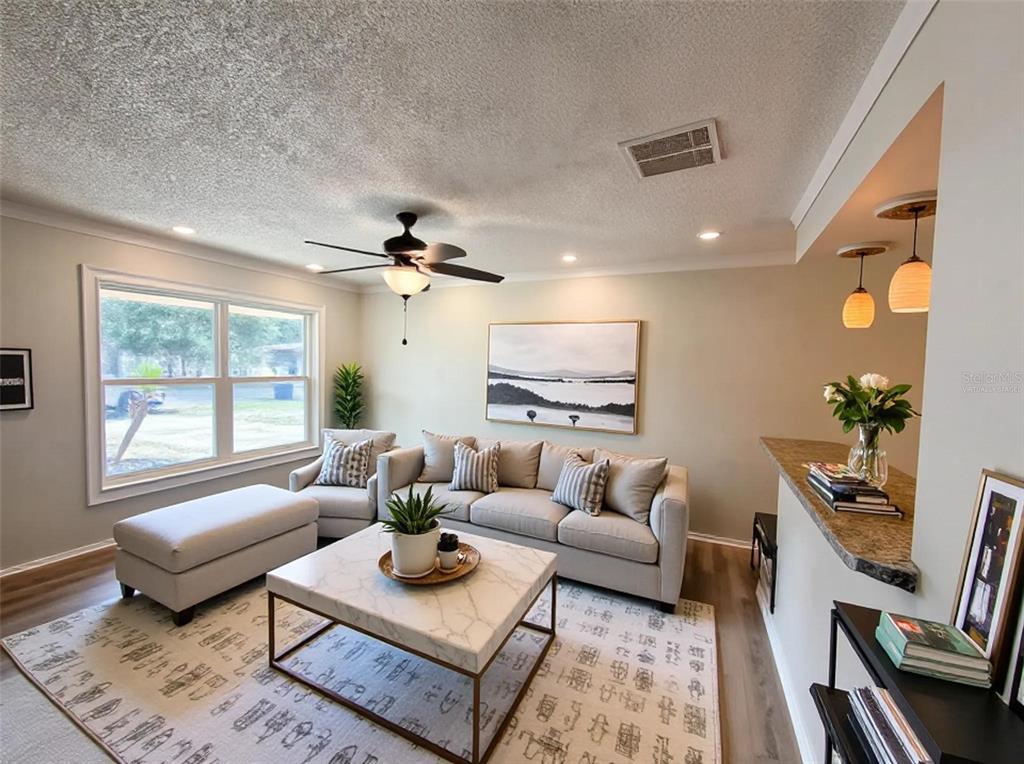 A living room features a sofa, ottoman, coffee table, ceiling fan, and a breakfast bar — 505 OAK DRIVE, TAVARES, FL