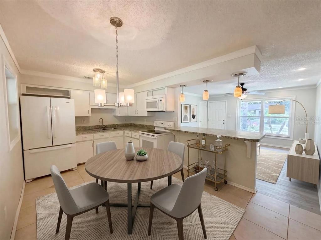 A kitchen with white cabinets, a round dining table, and a breakfast bar — 505 OAK DRIVE, TAVARES, FL