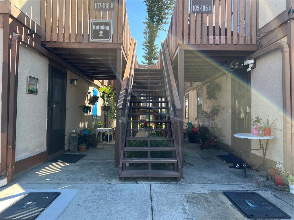 An exterior view of a two-story apartment building with a central wooden staircase — 5026 WATER OAK DRIVE UNIT 208, BRADENTON, FL