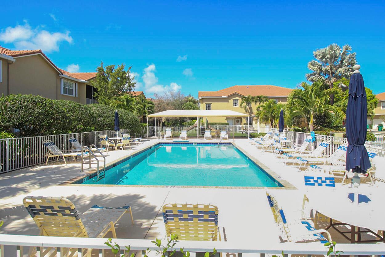 A swimming pool surrounded by lounge chairs and apartment buildings under a clear blue sky — 110 Lighthouse Circle # H, Tequesta FL 33469, TEQUESTA, FL