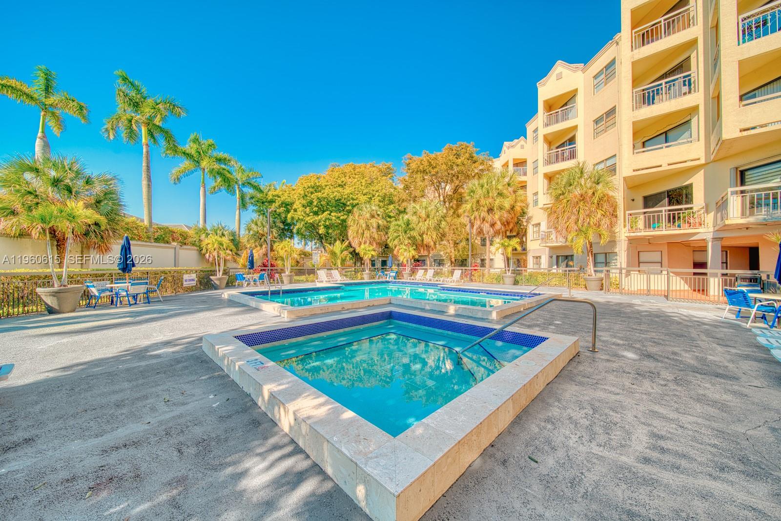An outdoor swimming pool and hot tub area with palm trees and a multi-story building — 8290 Lake Dr # 236, Doral FL 33166, DORAL, FL