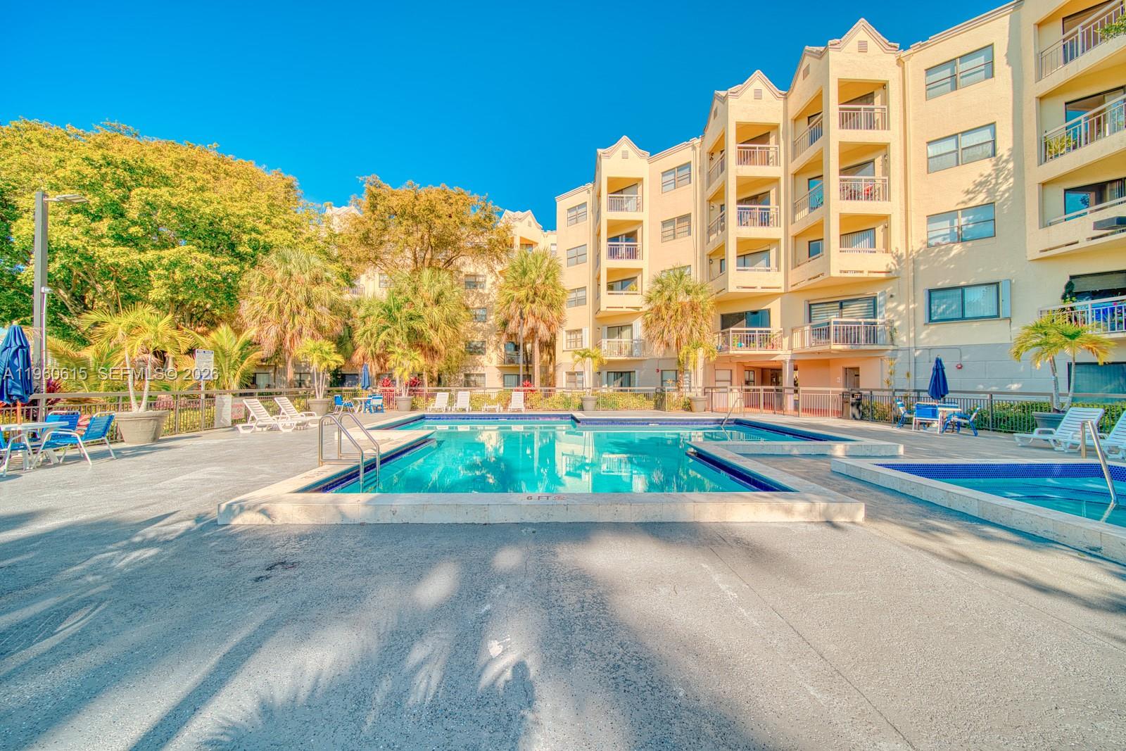 A swimming pool and hot tub are situated in the courtyard of a multi-story building — 8290 Lake Dr # 236, Doral FL 33166, DORAL, FL