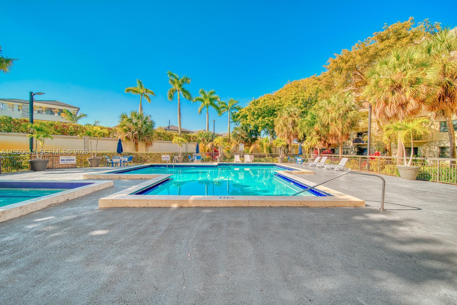 An outdoor swimming pool with a surrounding concrete deck, palm trees, and lounge chairs — 8290 Lake Dr # 236, Doral FL 33166, DORAL, FL