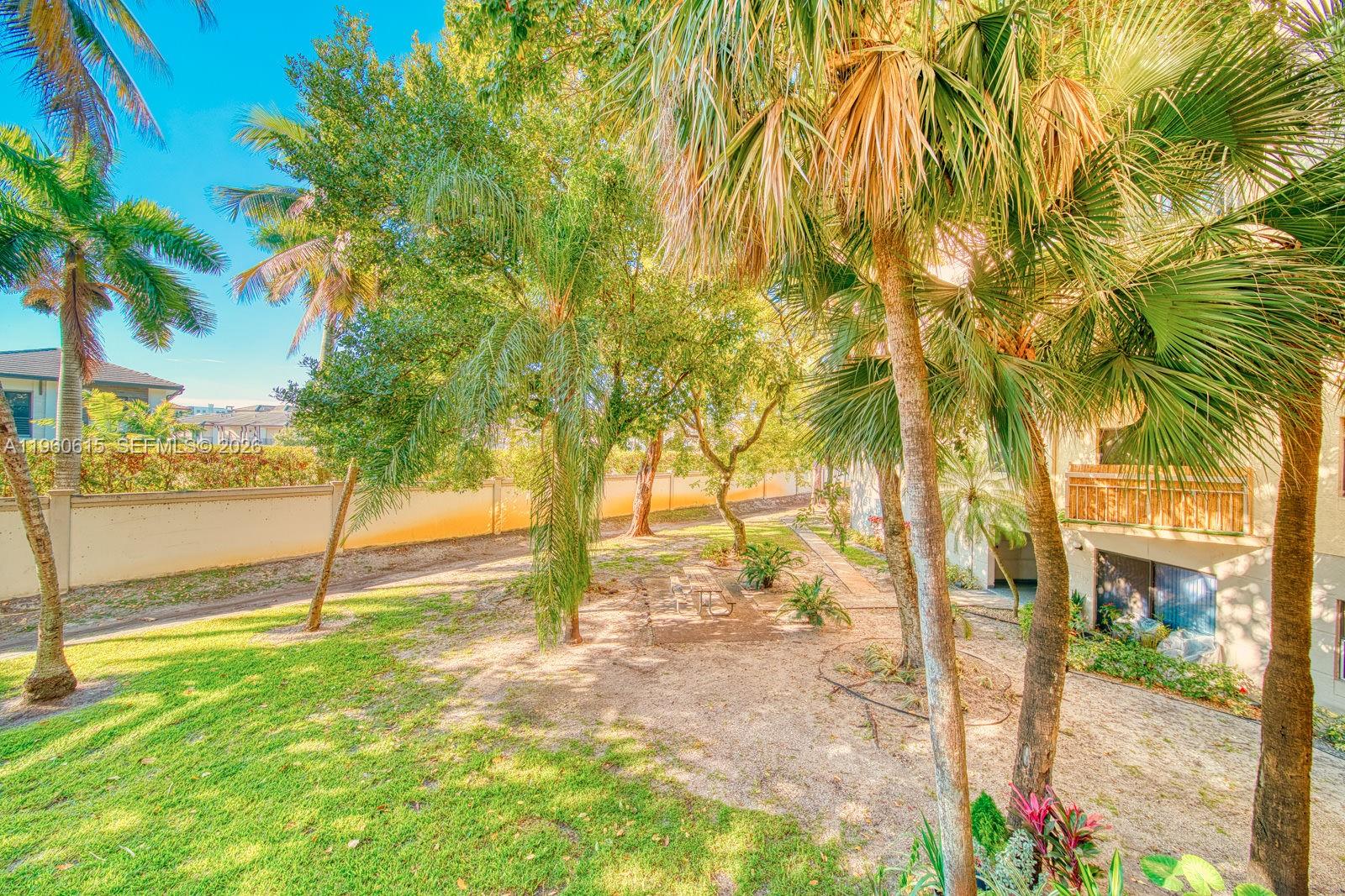A grassy backyard area features palm trees, a picnic table, and a perimeter wall — 8290 Lake Dr # 236, Doral FL 33166, DORAL, FL