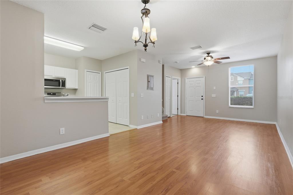 An open-concept living and dining area with wood-look flooring, a ceiling fan, and a kitchen — 1236 BLENHEIM COURT, WESLEY CHAPEL, FL
