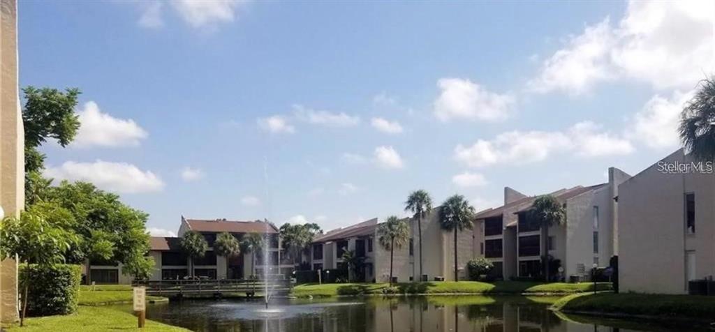 A pond with a fountain sits in front of multi-story apartment buildings and palm trees — 3850 N LAKE DRIVE UNIT 140, TAMPA, FL