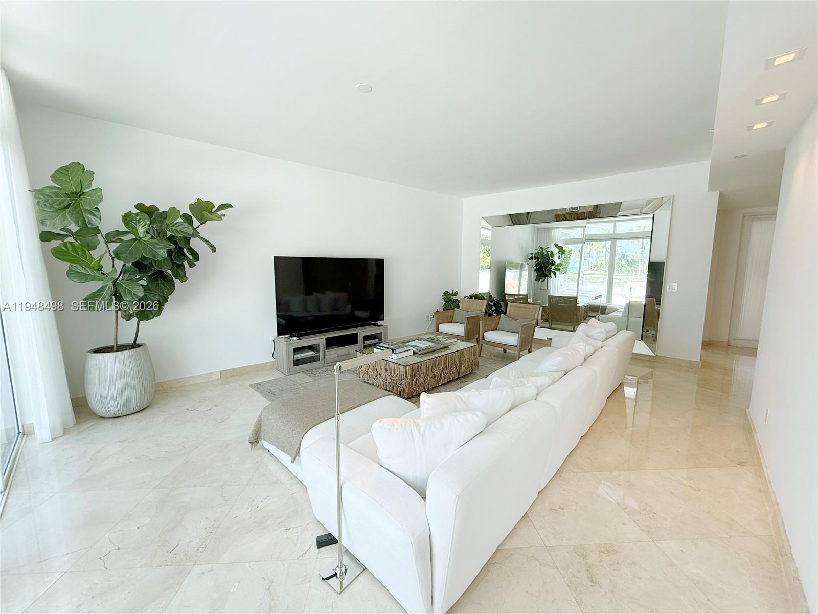 A bright living room features a white sectional sofa, a television, and polished marble floors — 50 S Pointe Dr, Miami Beach FL 33139, MIAMI BEACH, FL