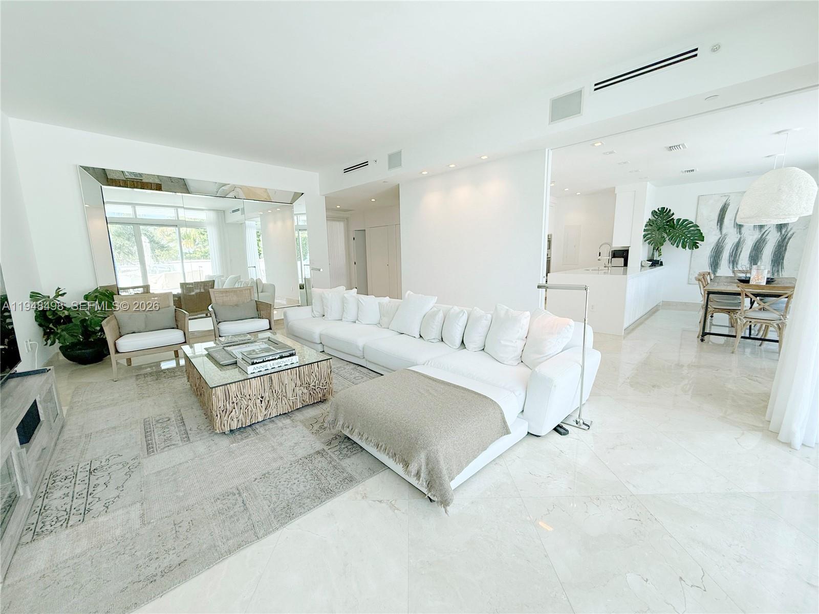 A bright, open-concept living room features a large white sectional, marble floors, and mirrored walls — 50 S Pointe Dr, Miami Beach FL 33139, MIAMI BEACH, FL
