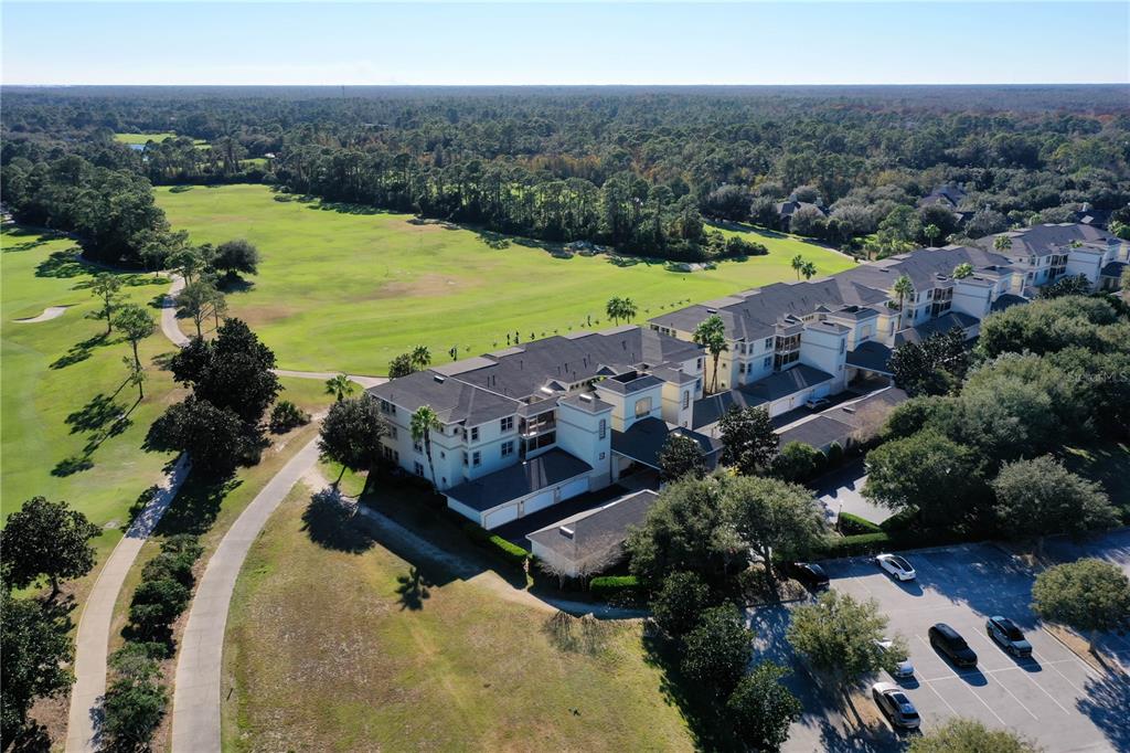 An aerial view shows a multi-story apartment building situated next to a golf course — 200 RIVERFRONT DRIVE UNIT D304, PALM COAST, FL
