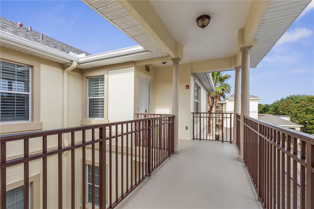 An outdoor walkway with brown metal railings and beige stucco walls under a covered roof — 200 RIVERFRONT DRIVE UNIT D304, PALM COAST, FL