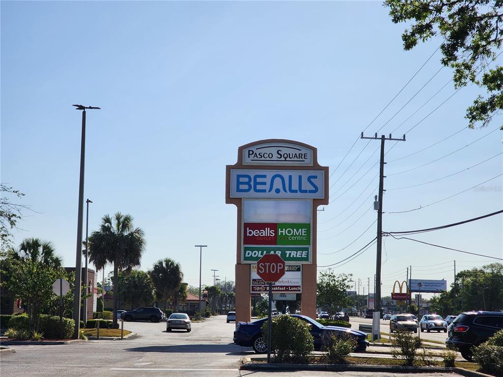 A tall, multi-tenant shopping center sign stands in a parking lot under a clear sky — SR 54, NEW PORT RICHEY, FL