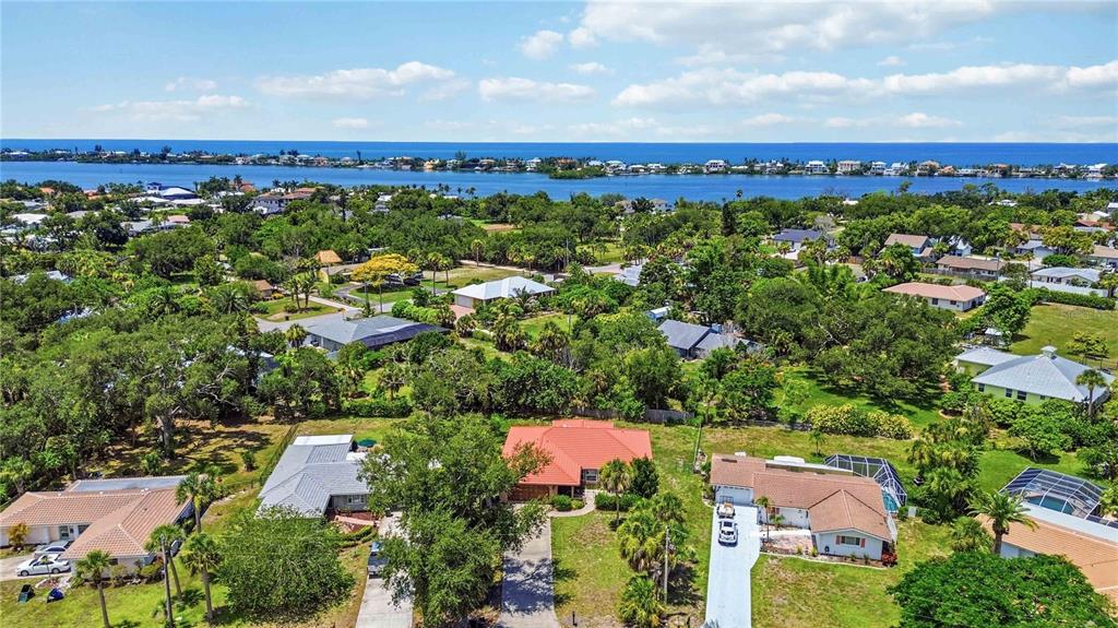 An aerial view shows several suburban houses surrounded by trees near a body of water — 2317 GOYA DRIVE, NOKOMIS, FL