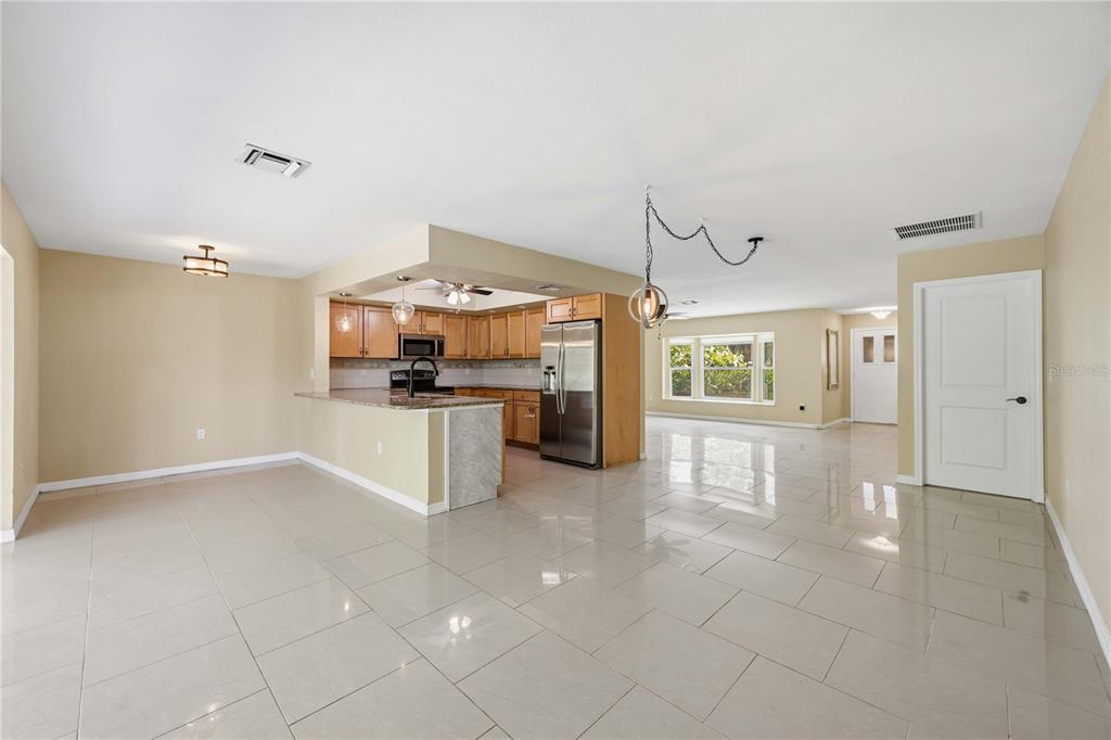 An open-concept kitchen and living area features light tile flooring and wood cabinetry — 2317 GOYA DRIVE, NOKOMIS, FL