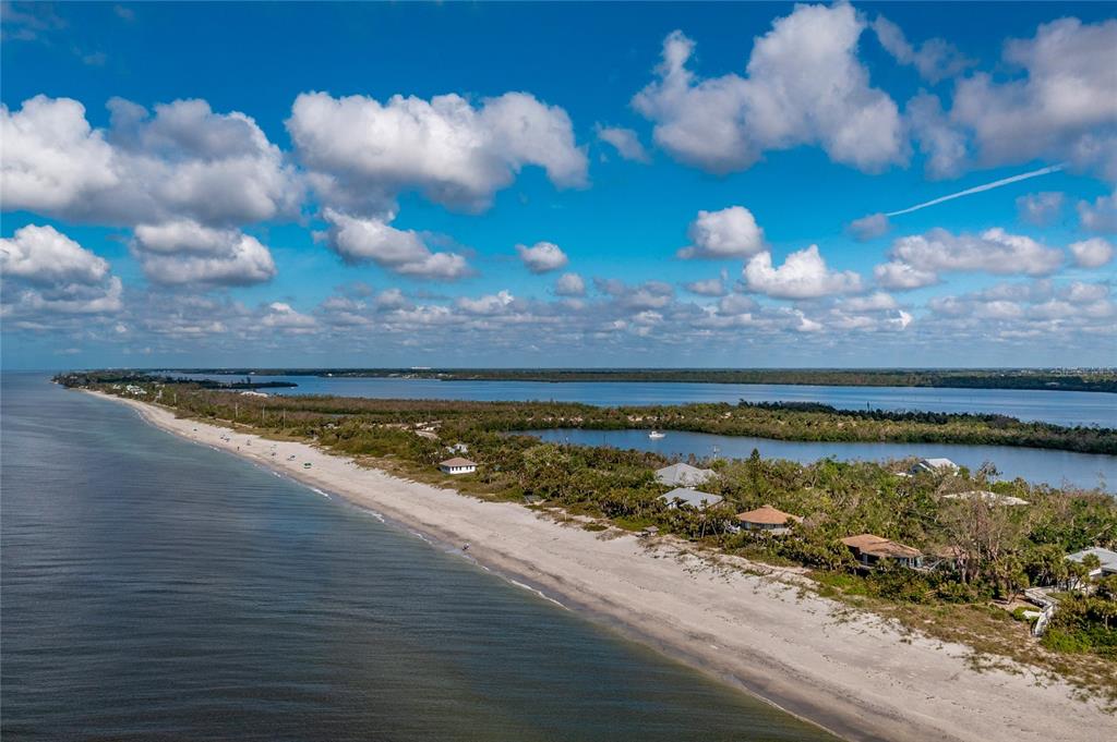 An aerial view shows a sandy beach bordering a narrow island with houses and vegetation — 6580 MANASOTA KEY ROAD, ENGLEWOOD, FL