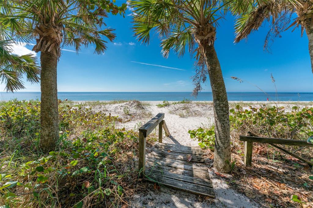 A wooden walkway leads through palm trees and dunes to a sandy beach and ocean — 6580 MANASOTA KEY ROAD, ENGLEWOOD, FL