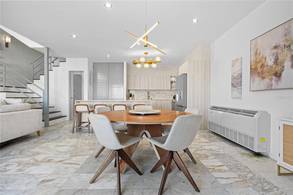 A dining area with a round wooden table, modern light fixtures, and marble tile flooring — 115 HARBOUR DRIVE UNIT 8, HUMACAO, PR
