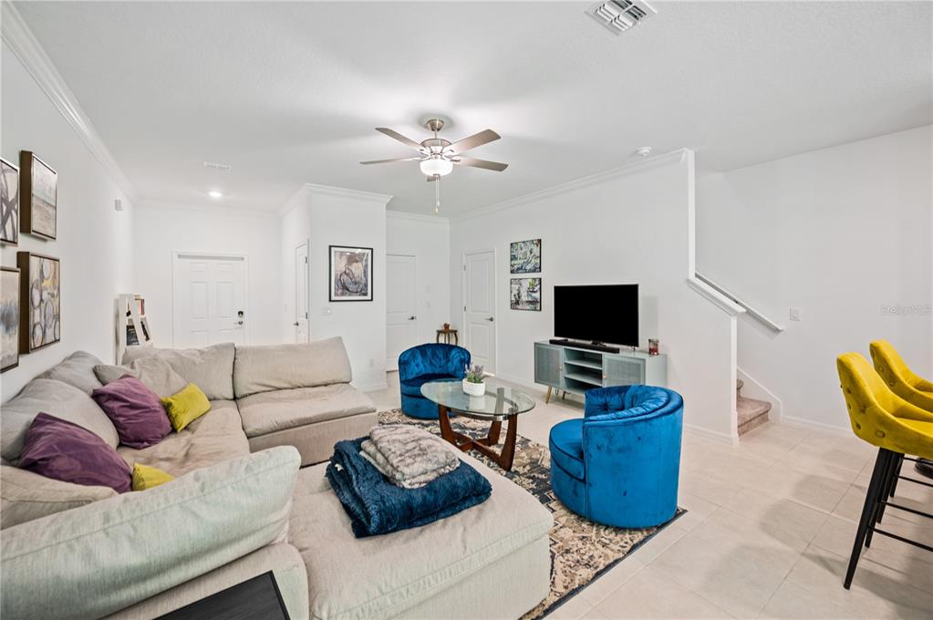 A living room features a large sectional sofa, two blue armchairs, and a television console — 17399 NECTAR FLUME DRIVE, LAND O LAKES, FL