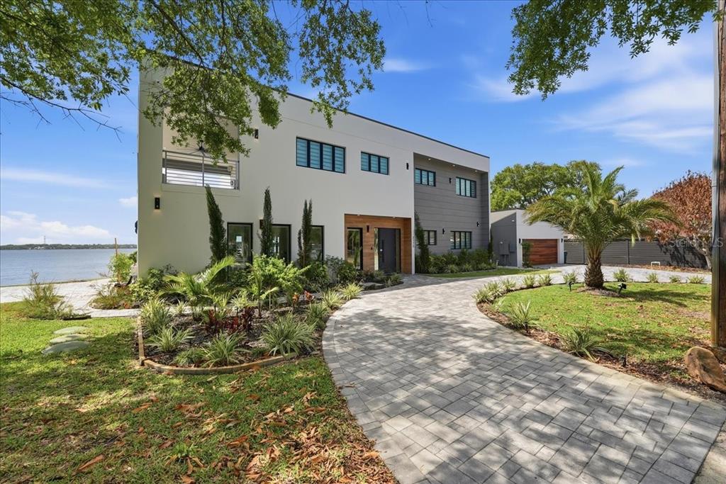 A modern two-story house with a paved driveway, landscaping, and a waterfront view — 2175 S TROPICAL TRAIL, MERRITT ISLAND, FL
