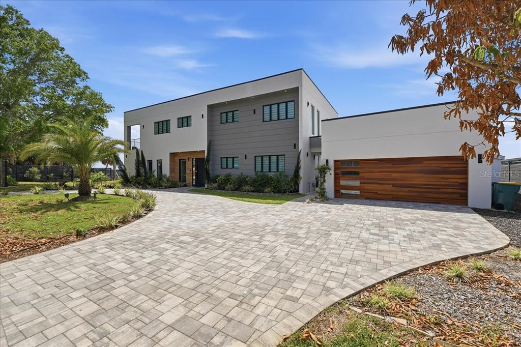 A modern two-story house with a paved driveway, wood garage door, and gray siding — 2175 S TROPICAL TRAIL, MERRITT ISLAND, FL