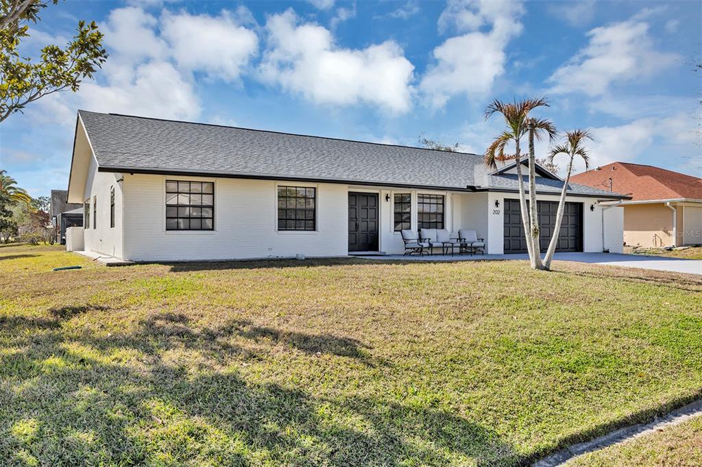 A single-story white house with a dark roof, black trim, and a front lawn — 202 SW HOLDEN TERRACE, PORT ST LUCIE, FL