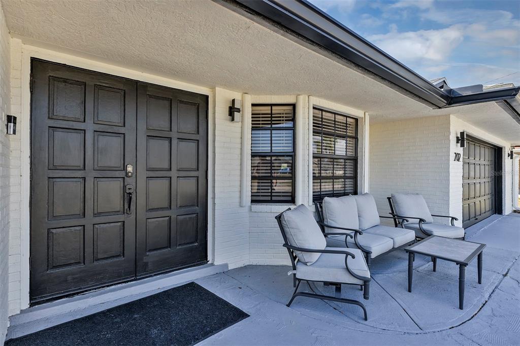 A white brick house exterior features a black double front door and a patio set — 202 SW HOLDEN TERRACE, PORT ST LUCIE, FL