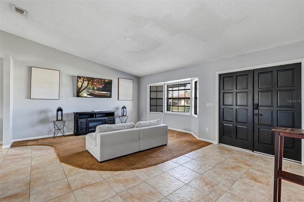 A living room features a white sofa on a brown rug, tile floors, and black doors — 202 SW HOLDEN TERRACE, PORT ST LUCIE, FL