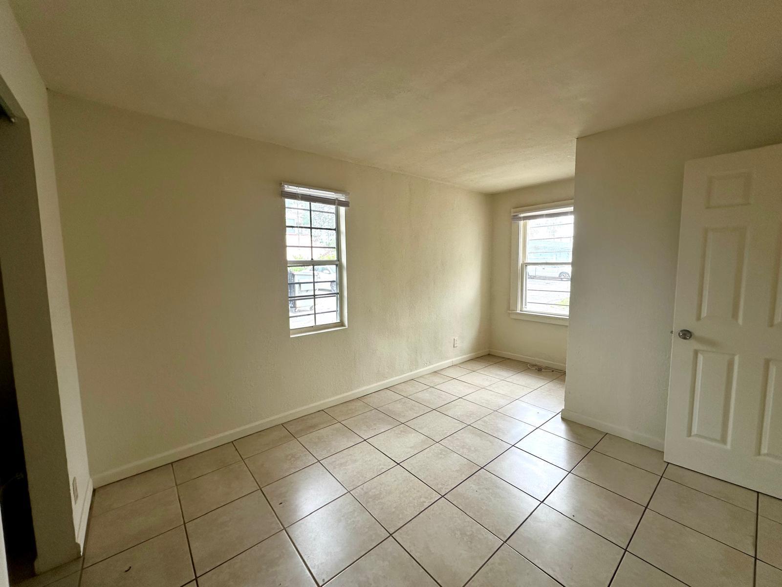An empty room with beige walls, tiled flooring, and two windows — 610 33rd Street, West Palm Beach FL 33407, WEST PALM BEACH, FL