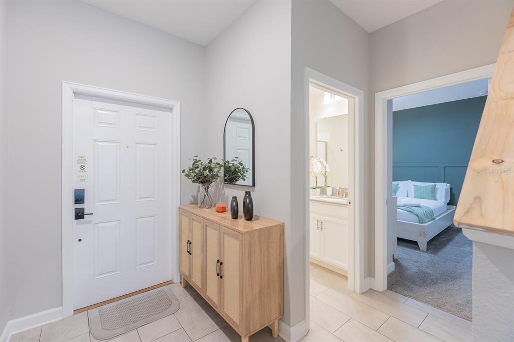 An entryway features a white door, a wooden console table, and views into a bathroom and bedroom — 4806 LULLABY LANE, KISSIMMEE, FL