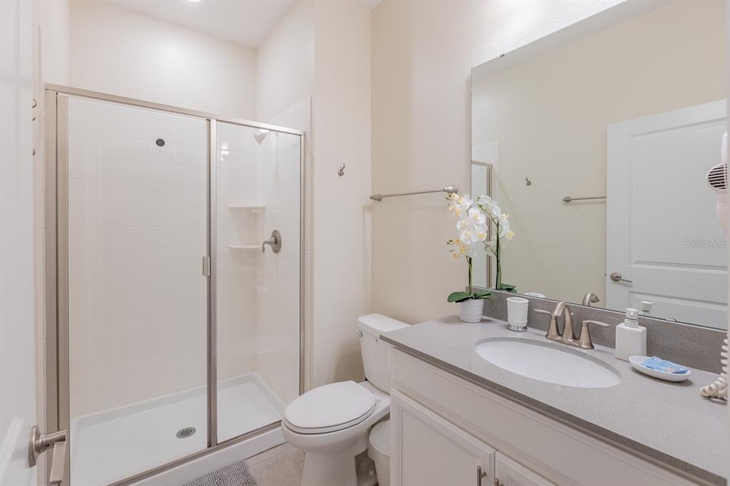 A bathroom features a glass-enclosed shower, a white toilet, and a single-sink vanity — 4806 LULLABY LANE, KISSIMMEE, FL