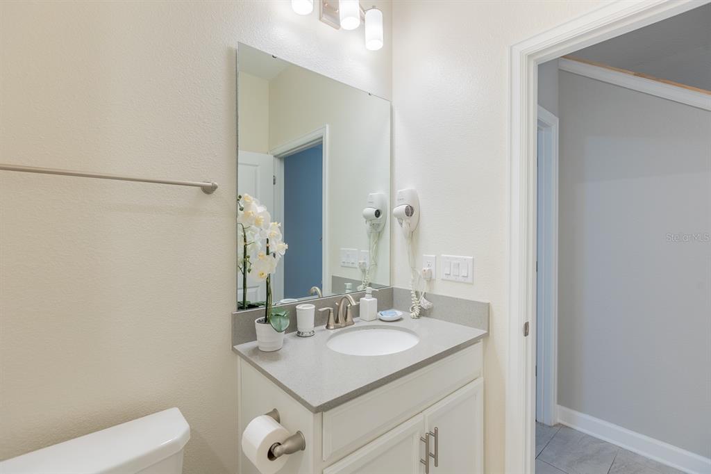 A bathroom features a white vanity with a gray countertop, a mirror, and a hair dryer — 4806 LULLABY LANE, KISSIMMEE, FL