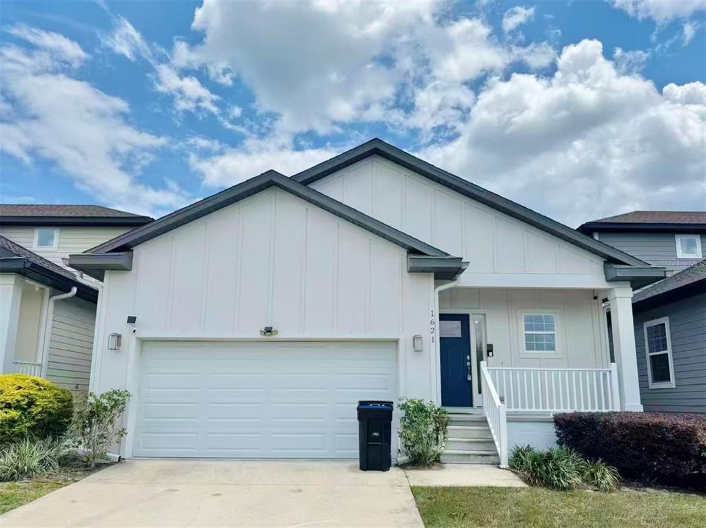 A single-story house with a white board-and-batten facade, a two-car garage, and a front porch — 1621 NW 121ST WAY, GAINESVILLE, FL