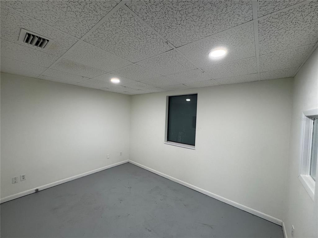 A small, empty room with white walls, a gray floor, and a drop ceiling — 702 W PARK AVENUE UNIT A1, EDGEWATER, FL