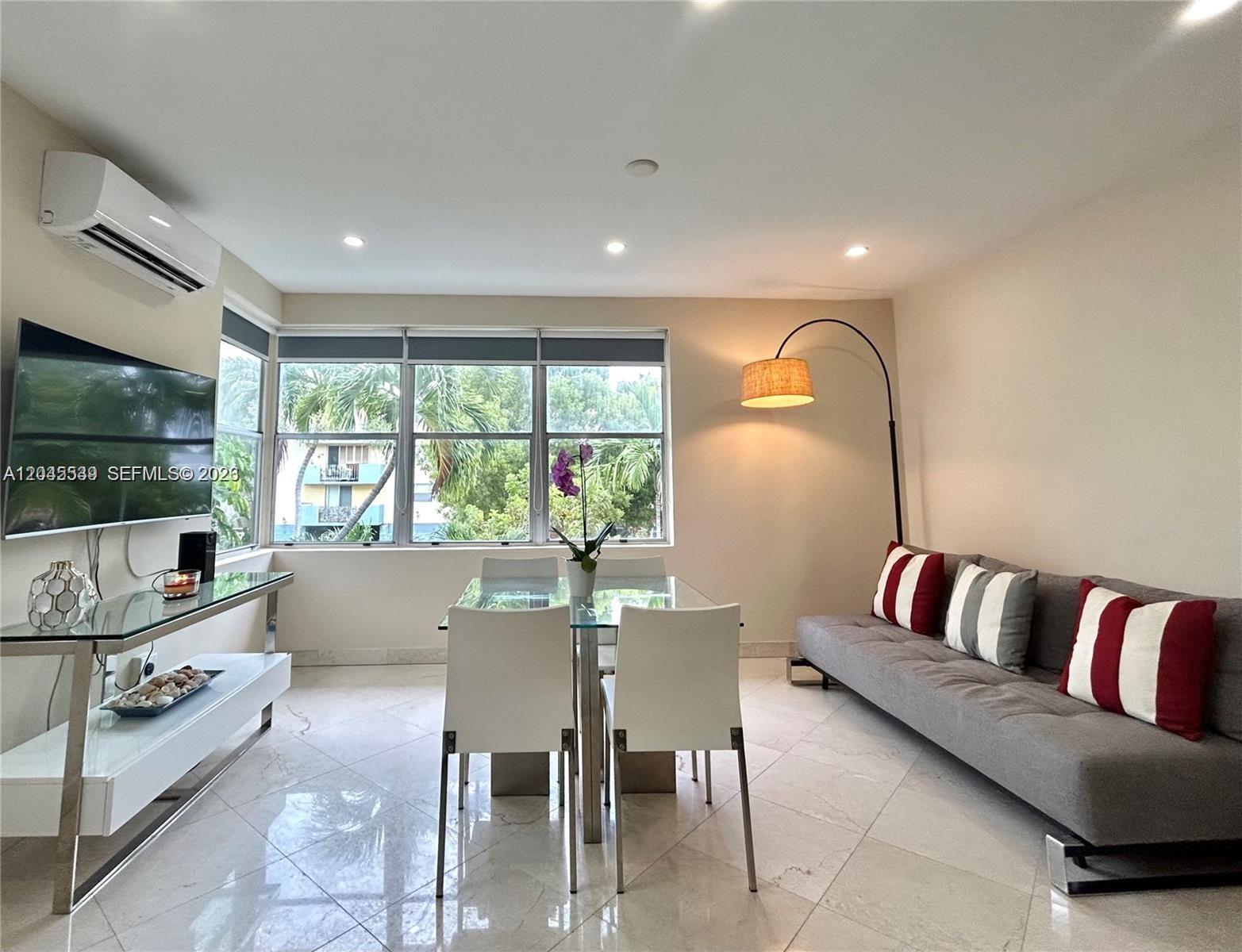 A living and dining area features a glass table, gray sofa, and large windows — 900 Jefferson Ave # 9, Miami Beach FL 33139, MIAMI BEACH, FL