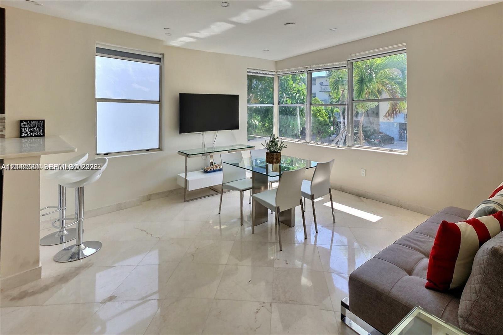 A bright living and dining area features tile floors, a glass table, and large windows — 900 Jefferson Ave # 9, Miami Beach FL 33139, MIAMI BEACH, FL