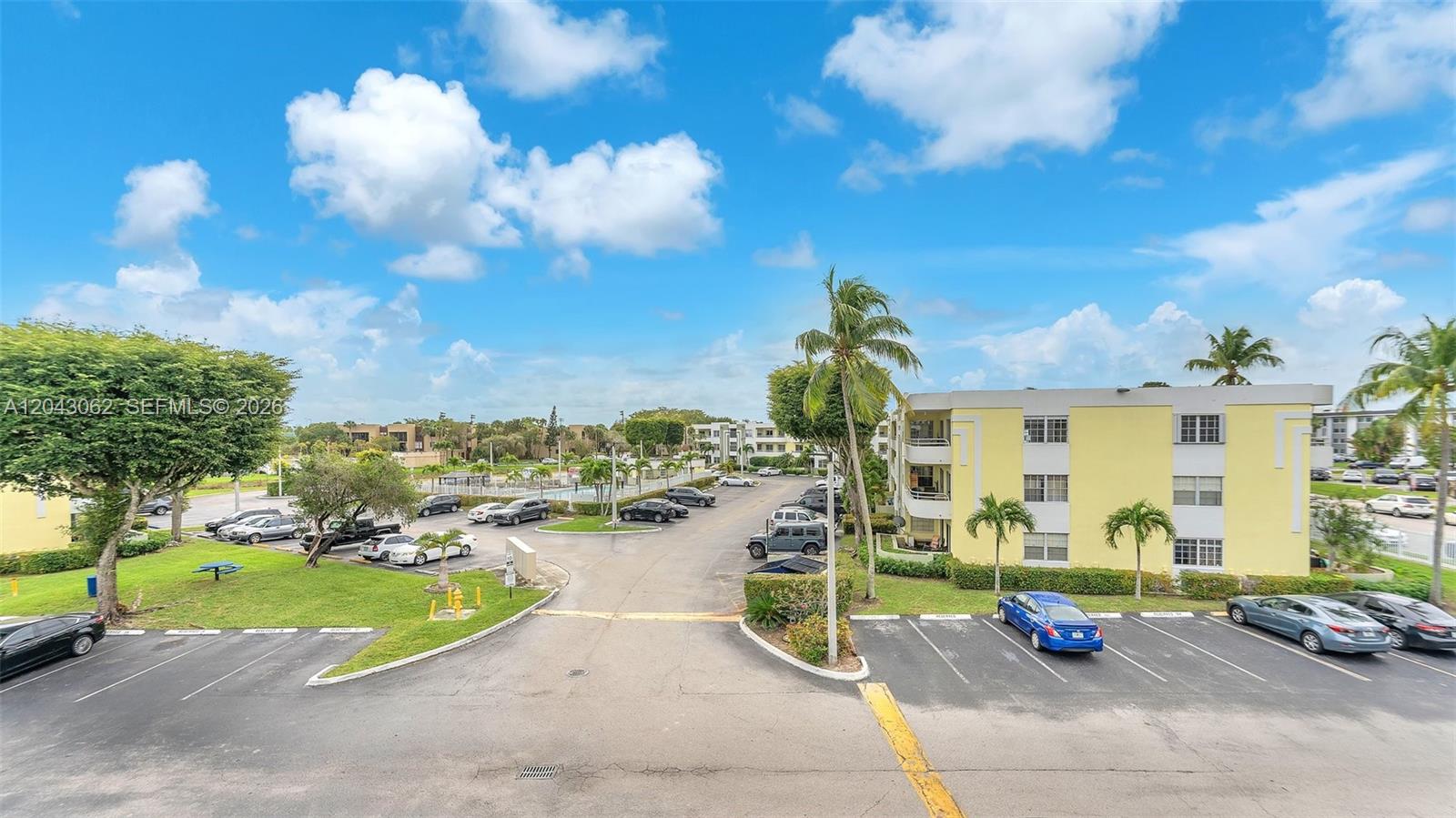 An outdoor view of a parking lot surrounded by apartment buildings and palm trees — 10755 SW 108th Ave # 304, Miami FL 33176, MIAMI, FL