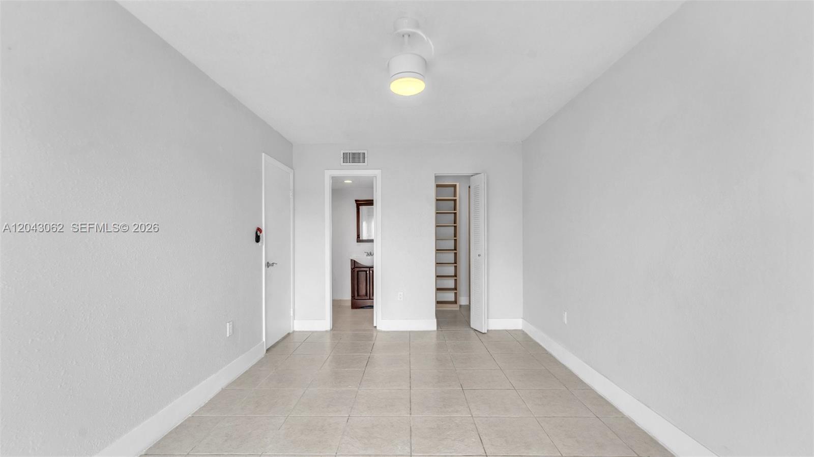 A room with light-colored walls, tile flooring, a ceiling light, and two open doorways — 10755 SW 108th Ave # 304, Miami FL 33176, MIAMI, FL