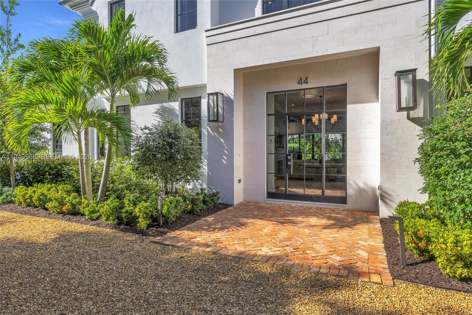A brick walkway leads to the glass-paned front entrance of a modern white house — 44 S Beach Rd, Hobe Sound FL 33455, HOBE SOUND, FL