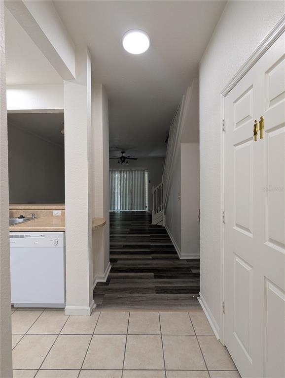 A hallway with tile flooring leads to a living area with wood-look floors and stairs — 4833 NW 46TH PLACE UNIT 106, GAINESVILLE, FL