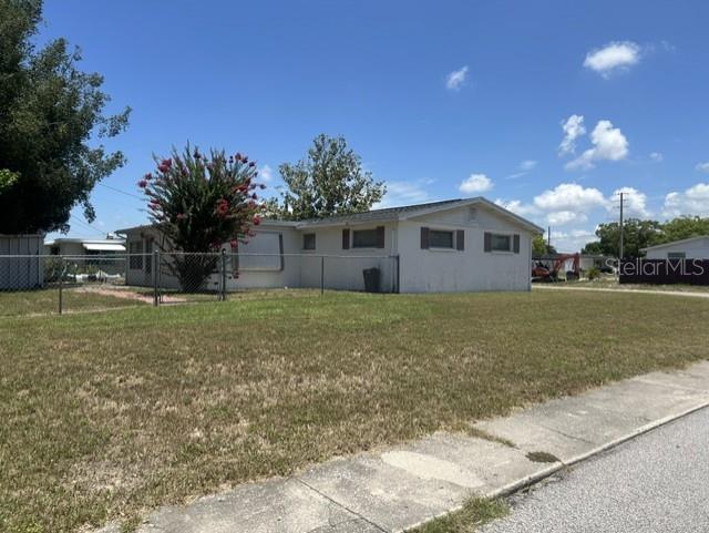 A single-story house with white siding stands behind a chain-link fence on a grassy lot — 3723 COLONIAL HILLS DRIVE, NEW PORT RICHEY, FL