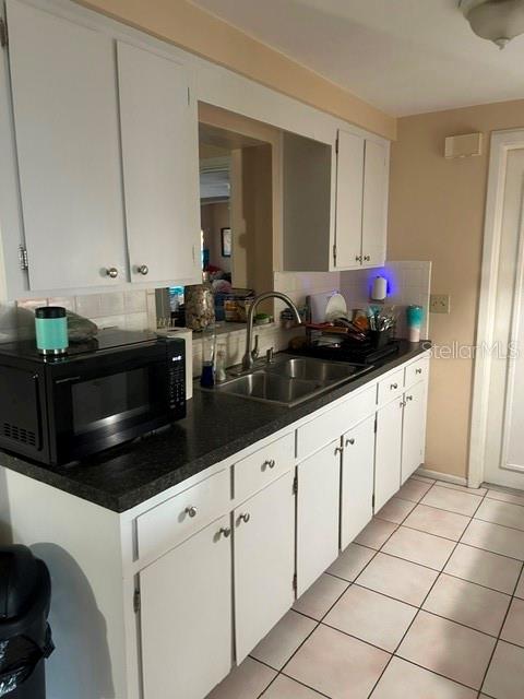 A kitchen features white cabinets, a black microwave, a double sink, and tiled flooring — 3723 COLONIAL HILLS DRIVE, NEW PORT RICHEY, FL