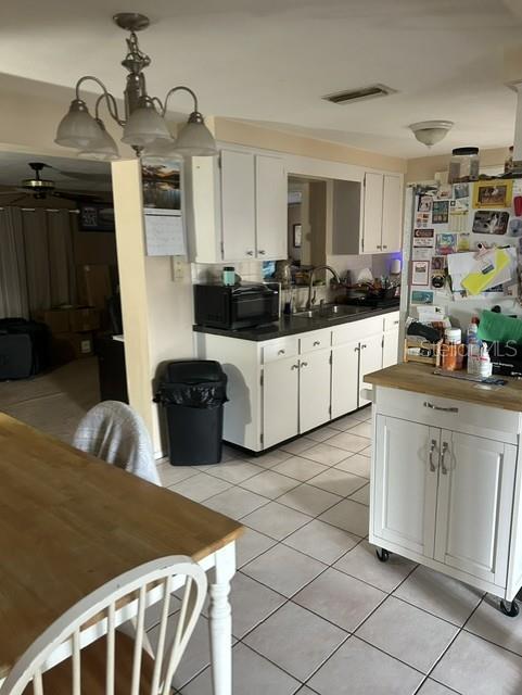 A kitchen features white cabinets, a wooden island, and a dining table on tiled floors — 3723 COLONIAL HILLS DRIVE, NEW PORT RICHEY, FL