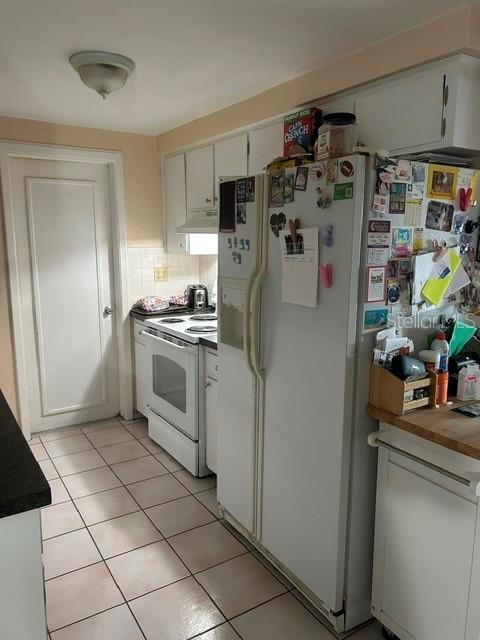 A kitchen features white cabinets, a white refrigerator, a white stove, and tiled flooring — 3723 COLONIAL HILLS DRIVE, NEW PORT RICHEY, FL