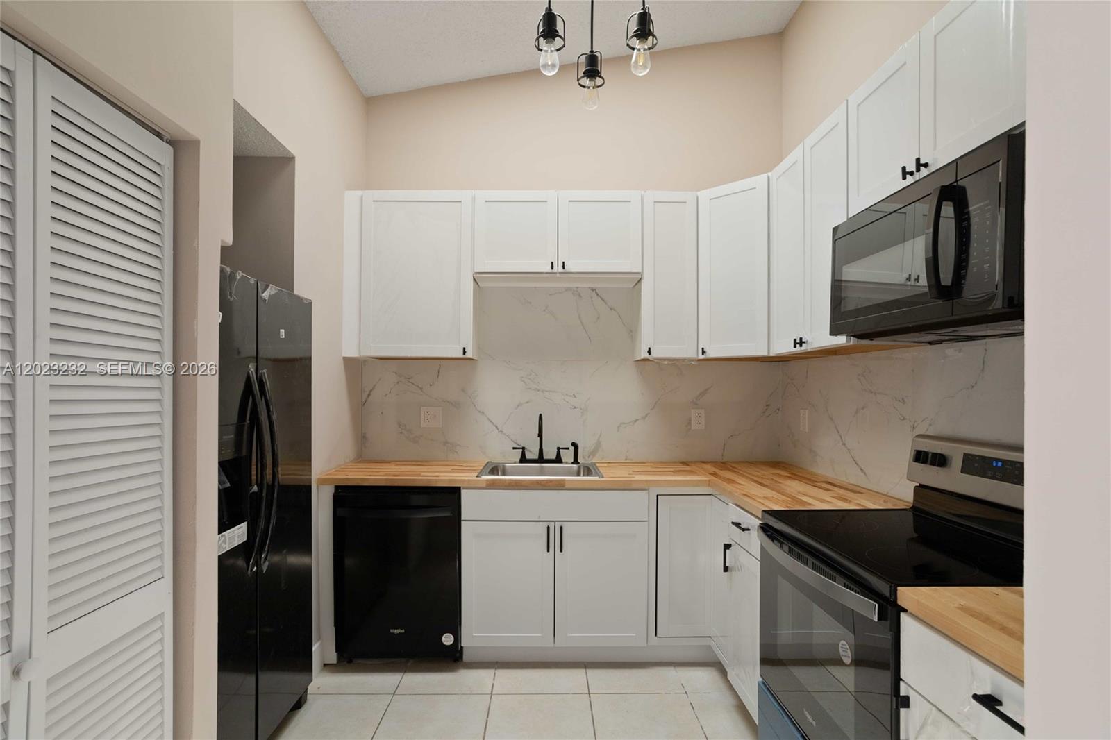 A room with light-colored tile flooring, beige walls, and an open doorway to a kitchen — 3633 NW 99th Ter # 7B, Sunrise FL 33351, SUNRISE, FL