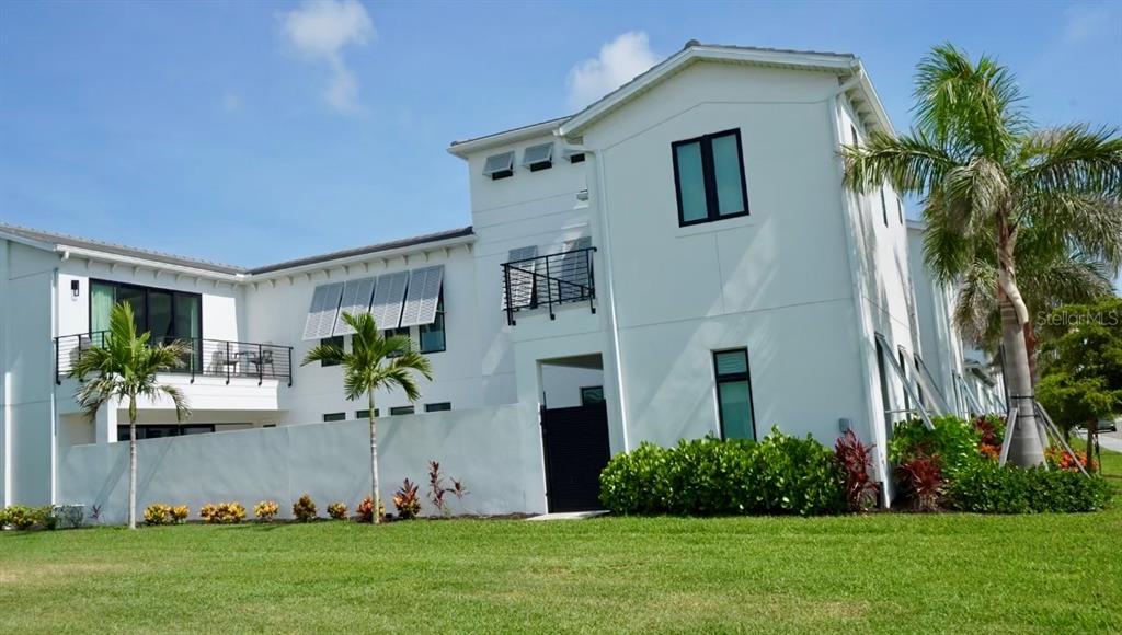 A white multi-story residential building features a black balcony, shutters, and surrounding palm trees — 6003 CAT CLAW LANE, BRADENTON, FL