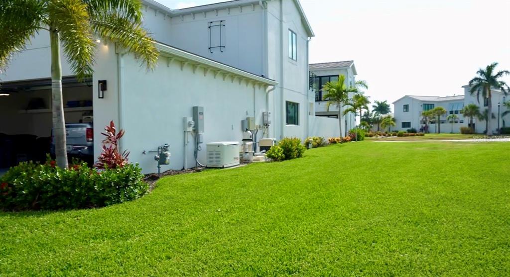 A white house exterior with a garage, lawn, and palm trees under a blue sky — 6003 CAT CLAW LANE, BRADENTON, FL